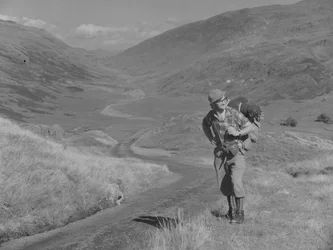 A man walking with a rucksack on his back in an open valley landscape