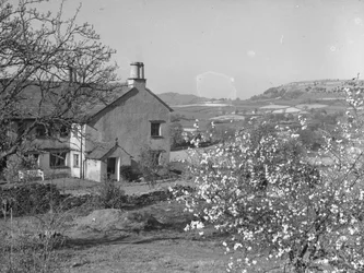 A partial view of a building surrounded by farmland