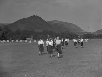 A view of women archers possibly part of a competition, fells in the background