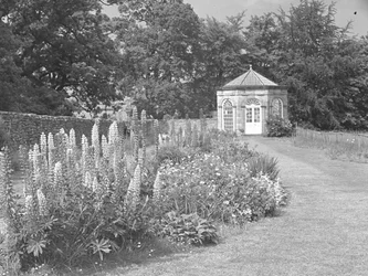 Summerhouse or folly in garden with lawn and flowerbeds
