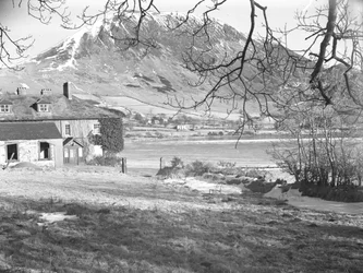 The Anglers Hotel at Ennerdale with trees in foreground and frozen lake and snowy fells beyond