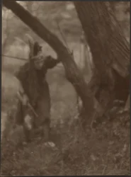 [Woman in Head Dress Behind Tree]