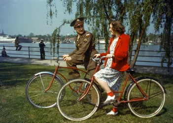Sitting on bicycles near a harbor, US Army officer flirts with a young woman on Trinidad