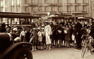 A group of students during a fieldtrip. The photograph shows the children, their teachers and other pedestrians on city street