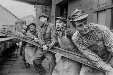 Mine workers pull together to move a heavy steel rail at El Teniente copper mine