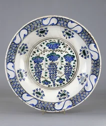 An Iznik pottery dish with a central roundel depicting three bunches of grapes and vine leaves, c.1570