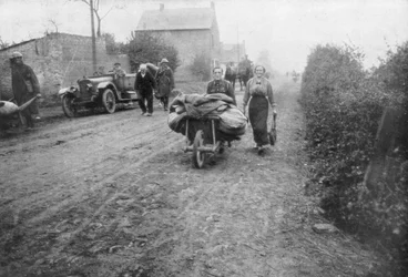A British soldier helping a woman return to her village, France, 1918