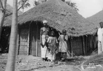 A family in front of their home, Gambia