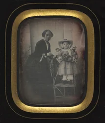 Child Standing on a Chair Holding Flowers, with Mother, c1855