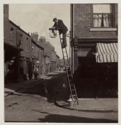 Man cleaning a gas street light, c 1905
