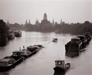 River barges on Chao Phraya River with a view of Wat Chaiwatthanaram
