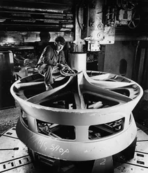 A fitter on top of a large cast item uses vertical boring machine