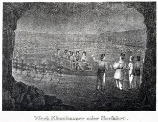 Salt mine: a group of visitors crossing the underground salt lake of the mine on a boat, in Durrnburg, Austria
