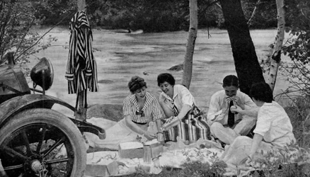 North America. Picnic party attack the luncheon basket during a motor trip to the Ozark mountains. 1920