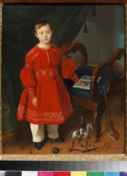 Portrait of a boy in a red dress with toys and an alphabet book