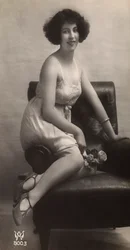 A young woman posing in her petticoat, sitting in an armchair
