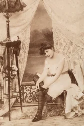 Portrait of a Young Woman in Intimate Apparel, Seated as She Laces Her Shoe