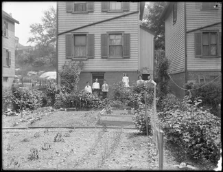 Family poses beside their backyard vegetable garden, Inwood, New York, c. 1910