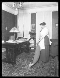 Unidentified woman demonstrating the use of the Apex vacuum cleaner, c.1913-14