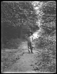 William Gray Hassler in Straw Hat and Overalls, Carrying Fishing Pole and Basket, Walking Down a Path in the Woods Alone