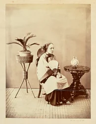 Studio Portrait of a Seated Young Woman Holding a Fan